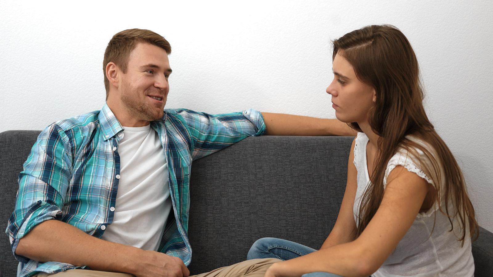 Man and woman having a serious talk while sitting on the couch