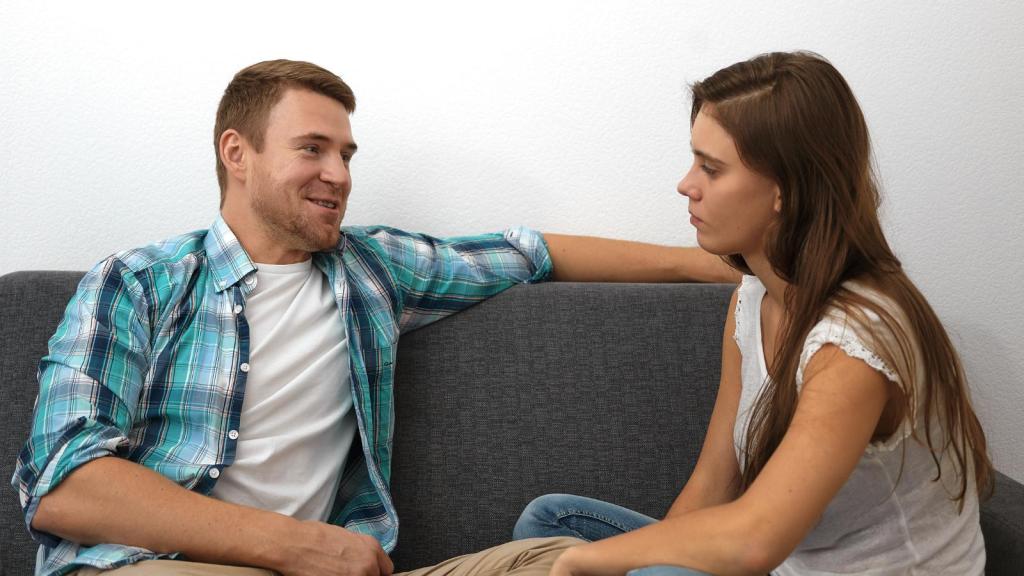 Man and woman having a serious talk while sitting on the couch