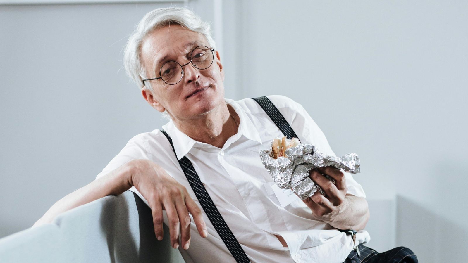 Older gentleman sitting and holding a sandwich wrapped in foil