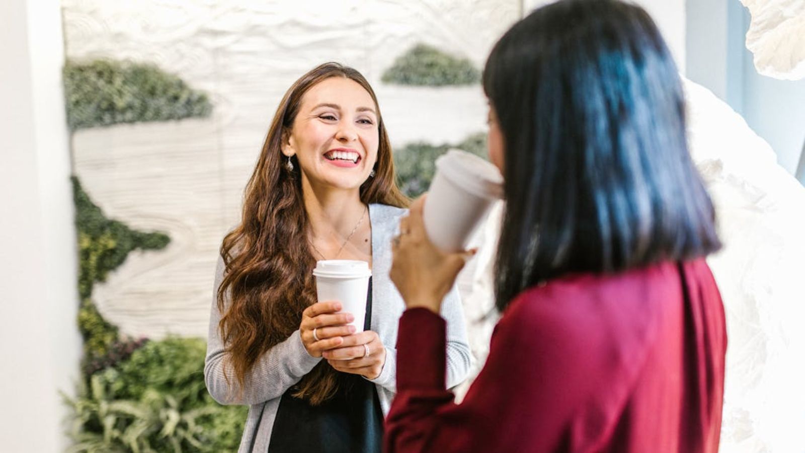 Female employees having a coffee break and one of them is laughing