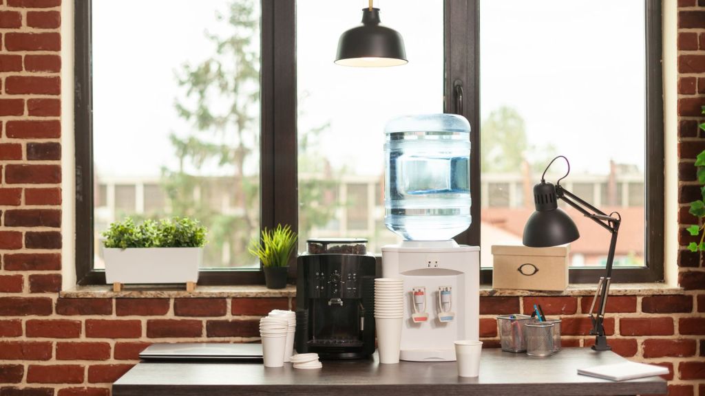 Water dispenser, coffee machine, and disposable cups on the office table