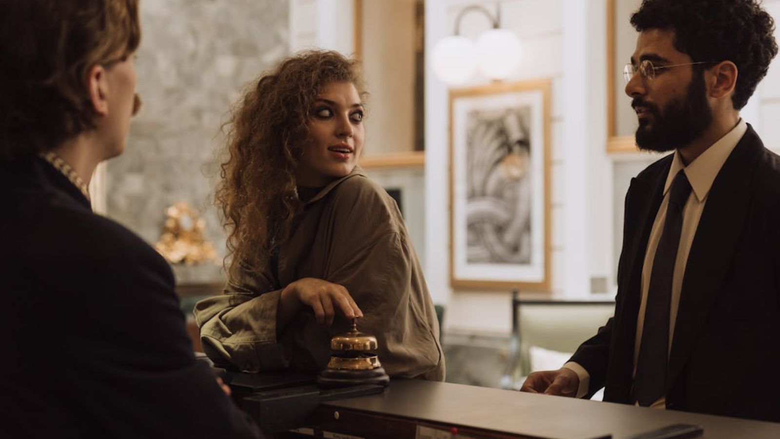 Male and female guests talking to a hotel front desk employee