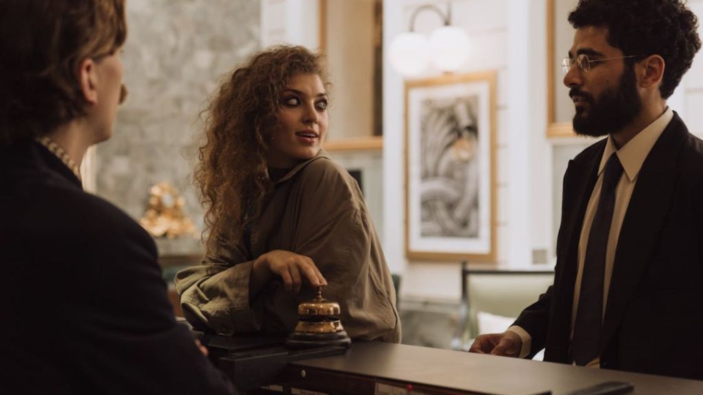 Male and female guests talking to a hotel front desk employee