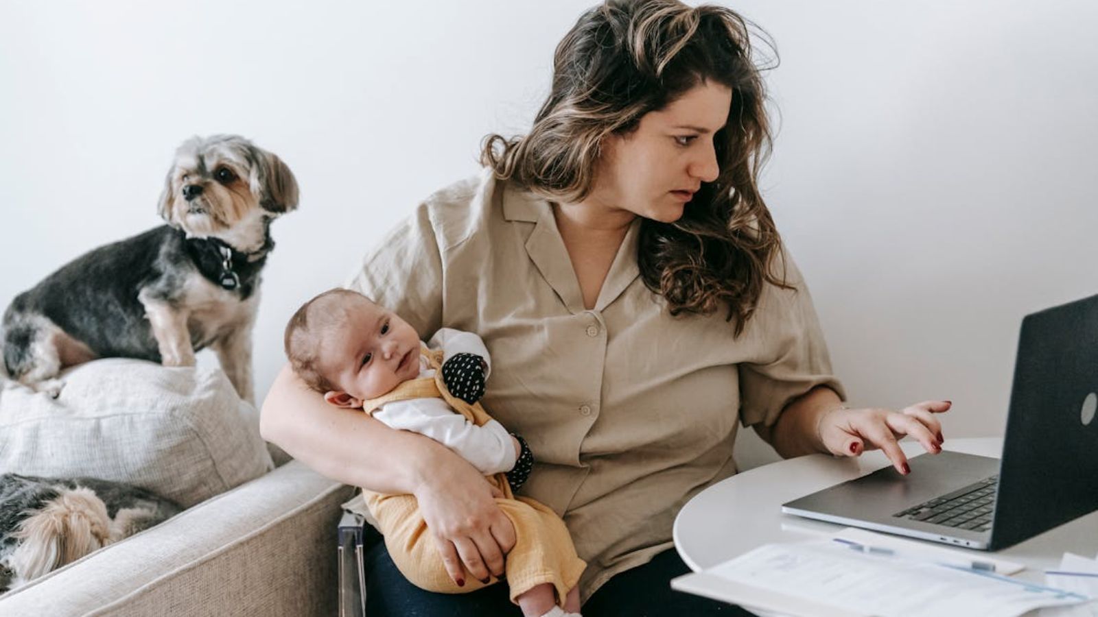 Woman carryng her baby while working on her laptop