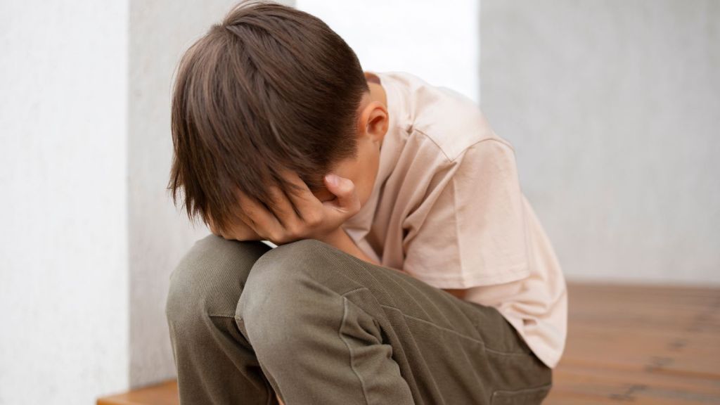 Boy crying and covering his face