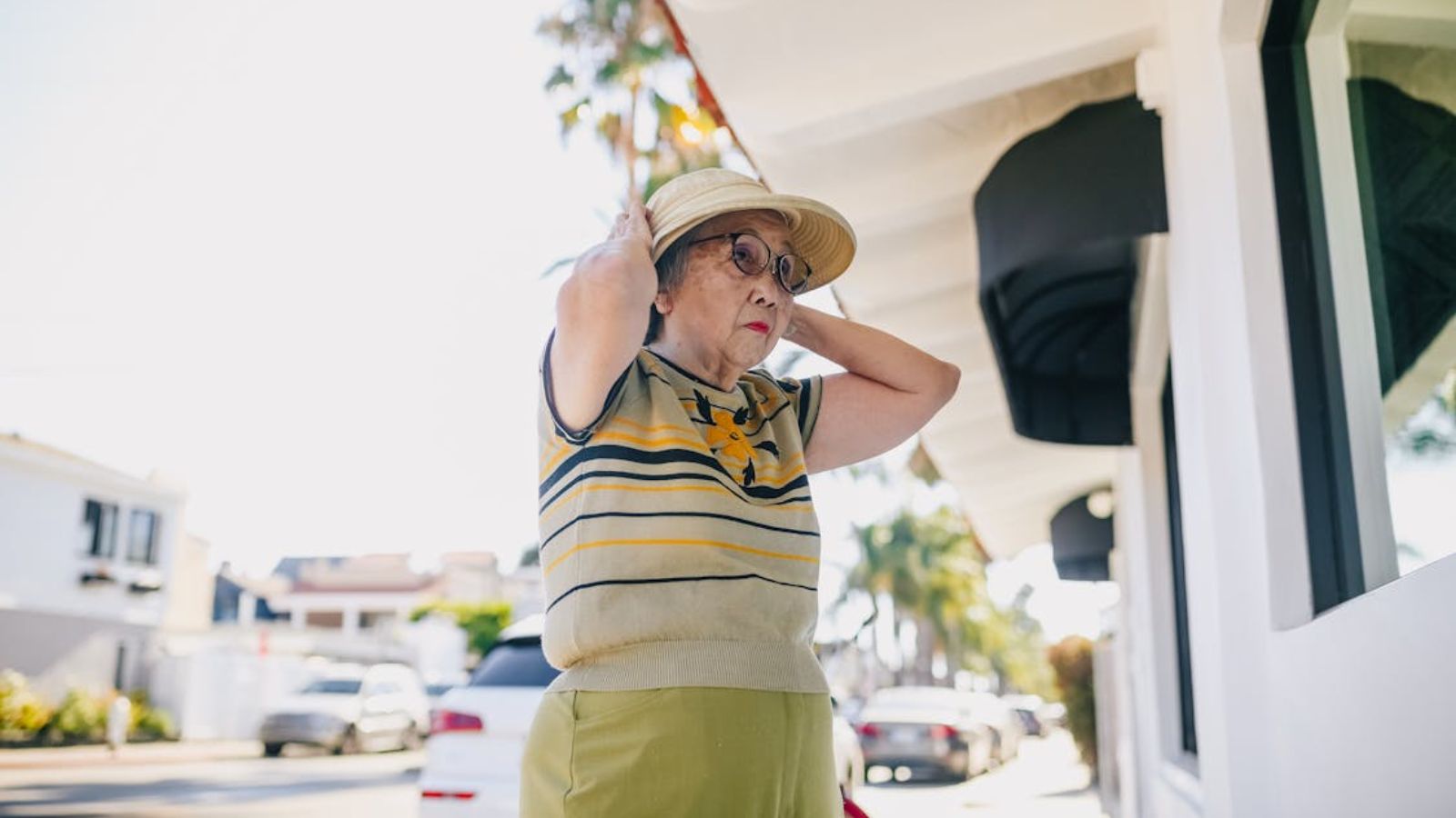 He Closed on a New House and Instantly Discovered His Neighbor Was Going to Be a Nightmare Old woman adjusting her hat on a sunny city street