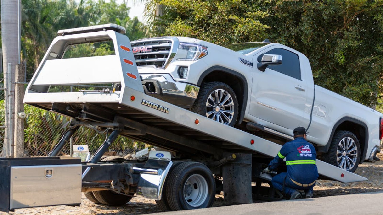 A white pickup truck being towed by the road