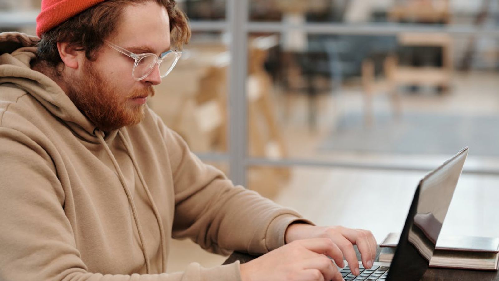 College student working on a report using his laptop in the library
