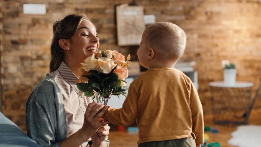 A toddler givng flowers to his mom