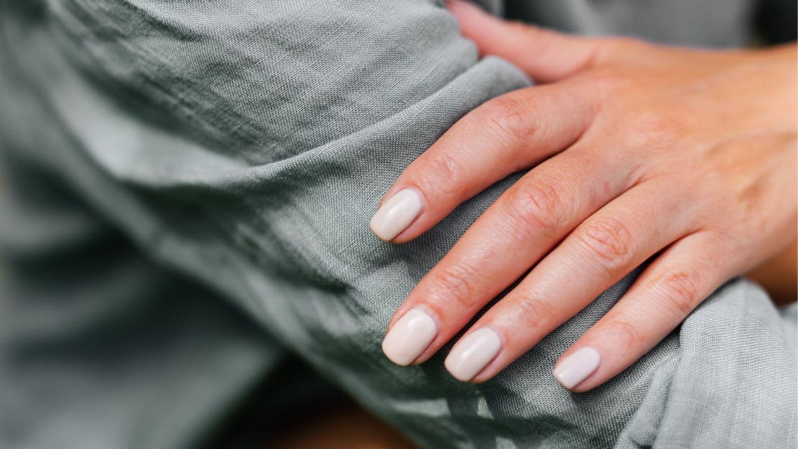 She Attended Her Brother’s Wedding as a Groomsman Wearing All Black, but the Bride Blamed Her for Her White Nails Woman' hand with white nails resting on her green sleeve