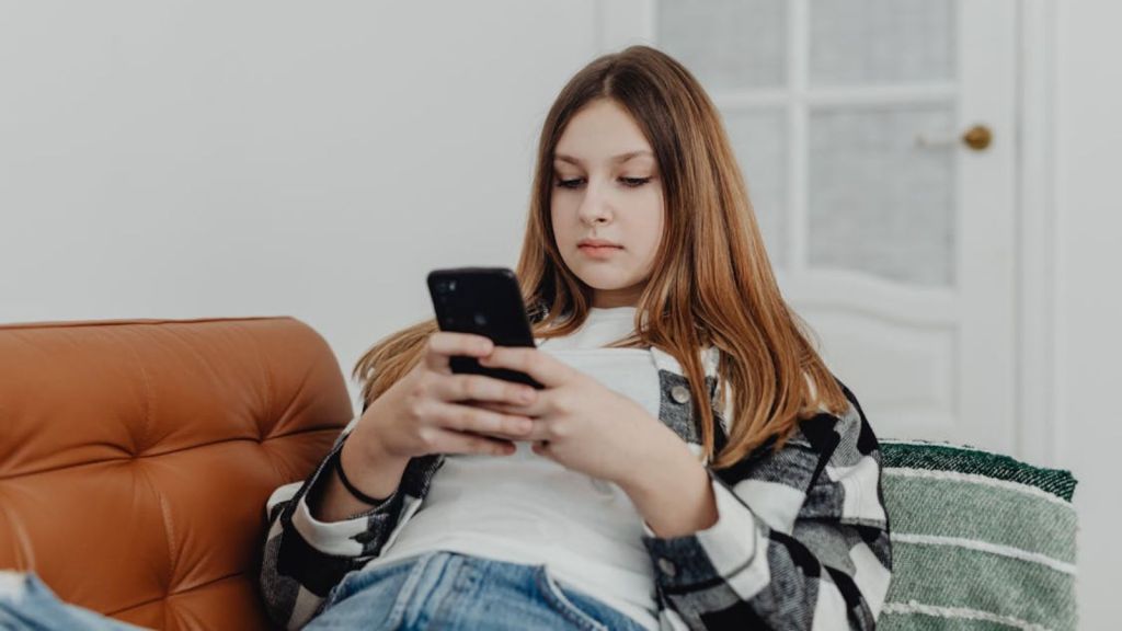 Teenage girl using her phone while sitting on the sofa