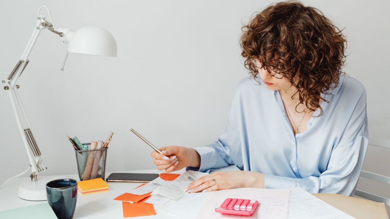 Woman calculating expenses with documents, calculator, and coffee