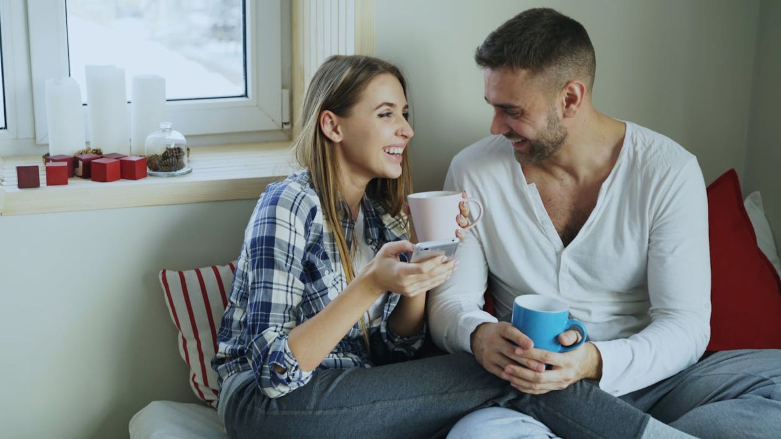 Woman Plans to Start a Family After Her Wedding, but Sister Asks Her to Wait Until 2027 Happy couple enjoying coffee and conversation indoors by the window