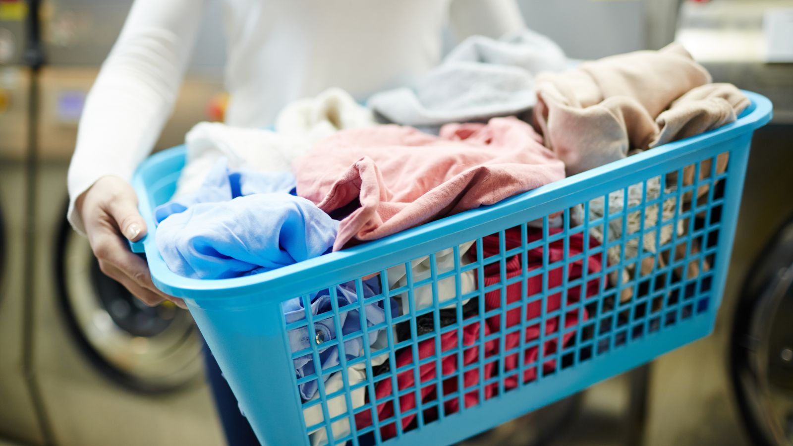 Person holding a basket of clean clothes after being washed in the washing machine