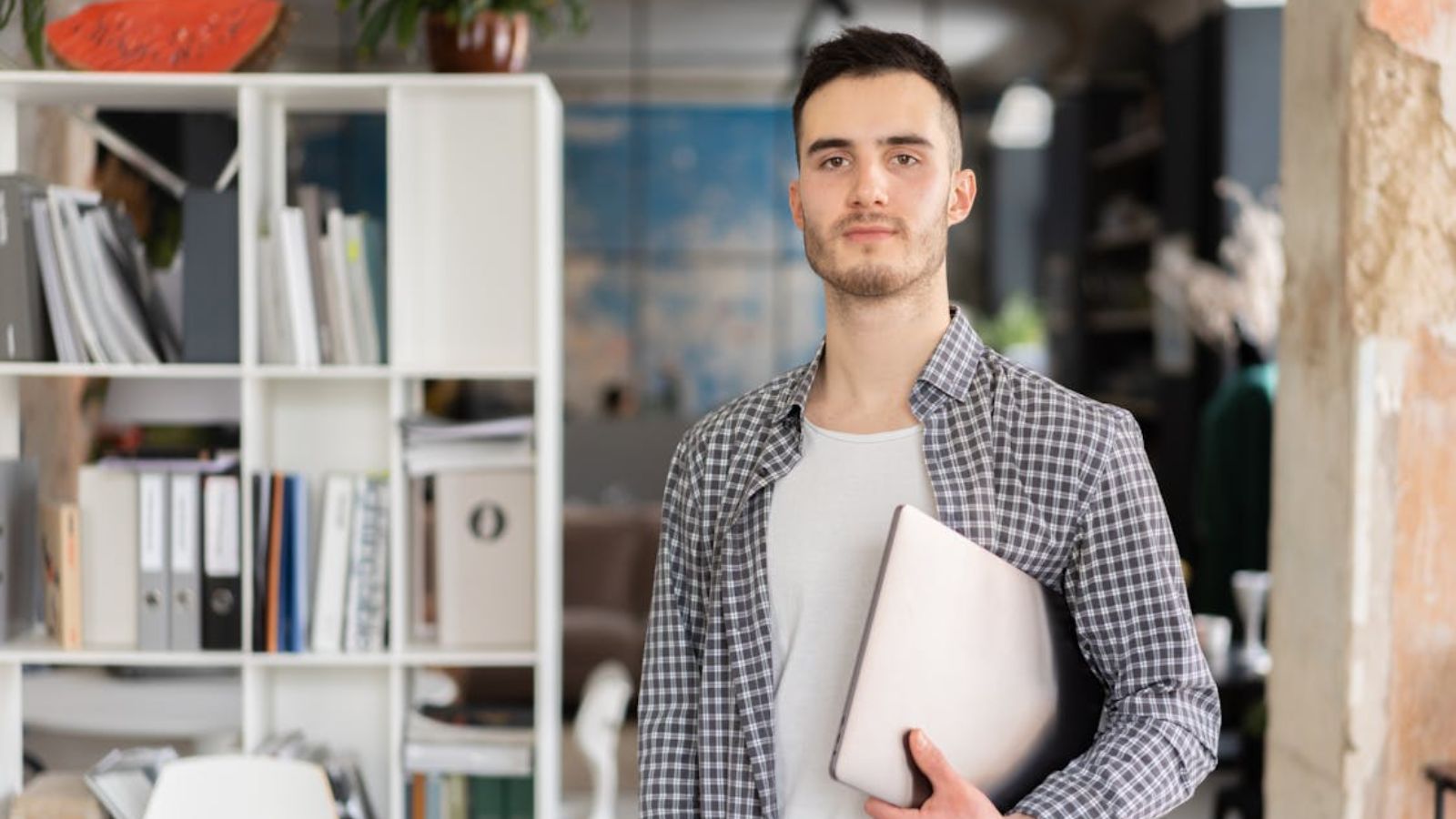 Man wearing a checkered shirt carrying a laptop
