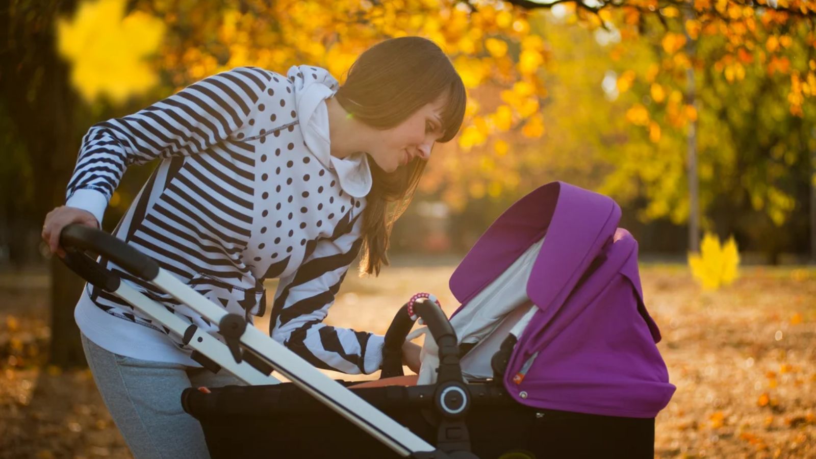 Mom Snaps at a Stranger Who Got Too Close to Her Baby With a Lit Cigarette Downtown Mother smiling down at her baby in a stroller during an autumn stroll in a park