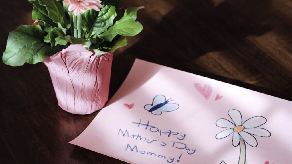 Pink flower and Mother's Day drawing on wooden tabl