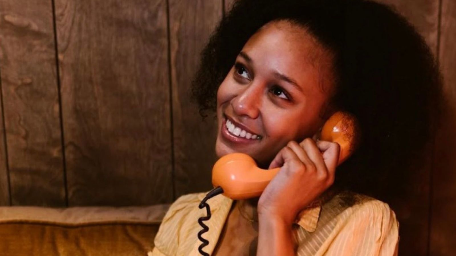 A Family Kept Getting Calls for a Defunct Auto Shop—So the Dad Started Booking Fake Appointments smiling woman talking on landline phone with a cord