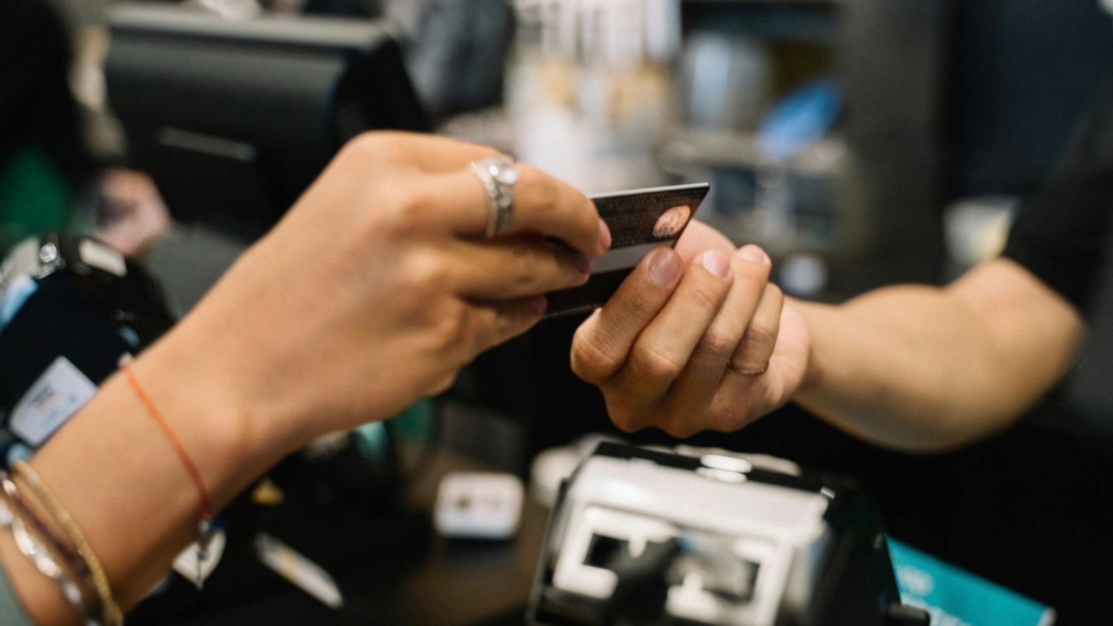 woman handing another woman a credit card