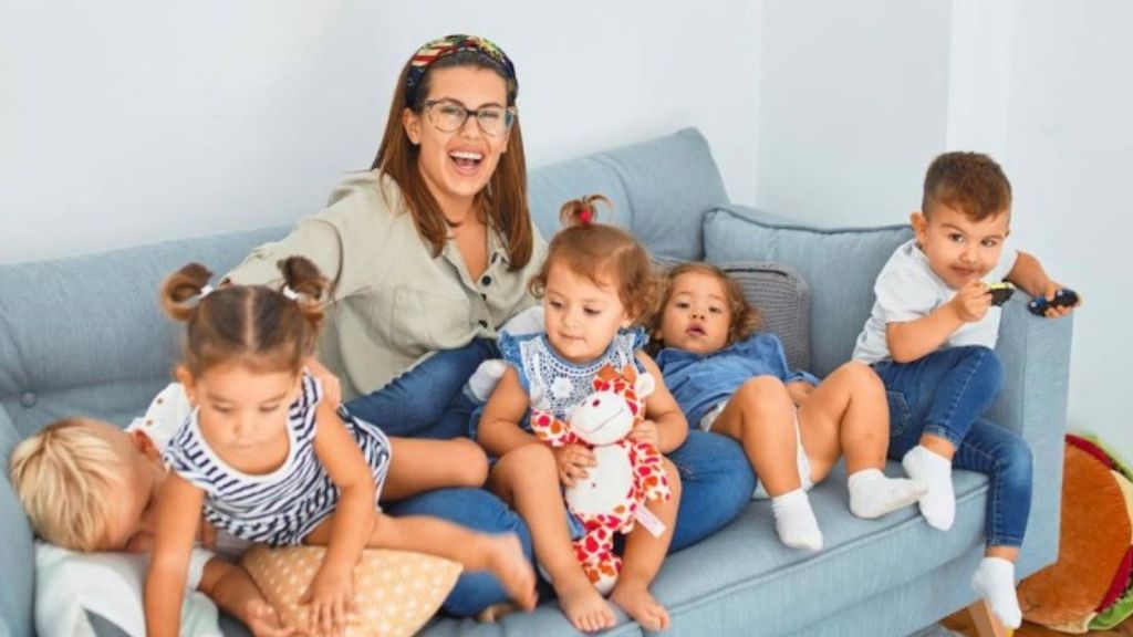 woman sitting on couch with five little kids