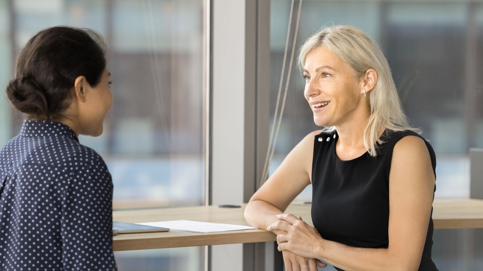 smiling older woman talking to younger woman at work
