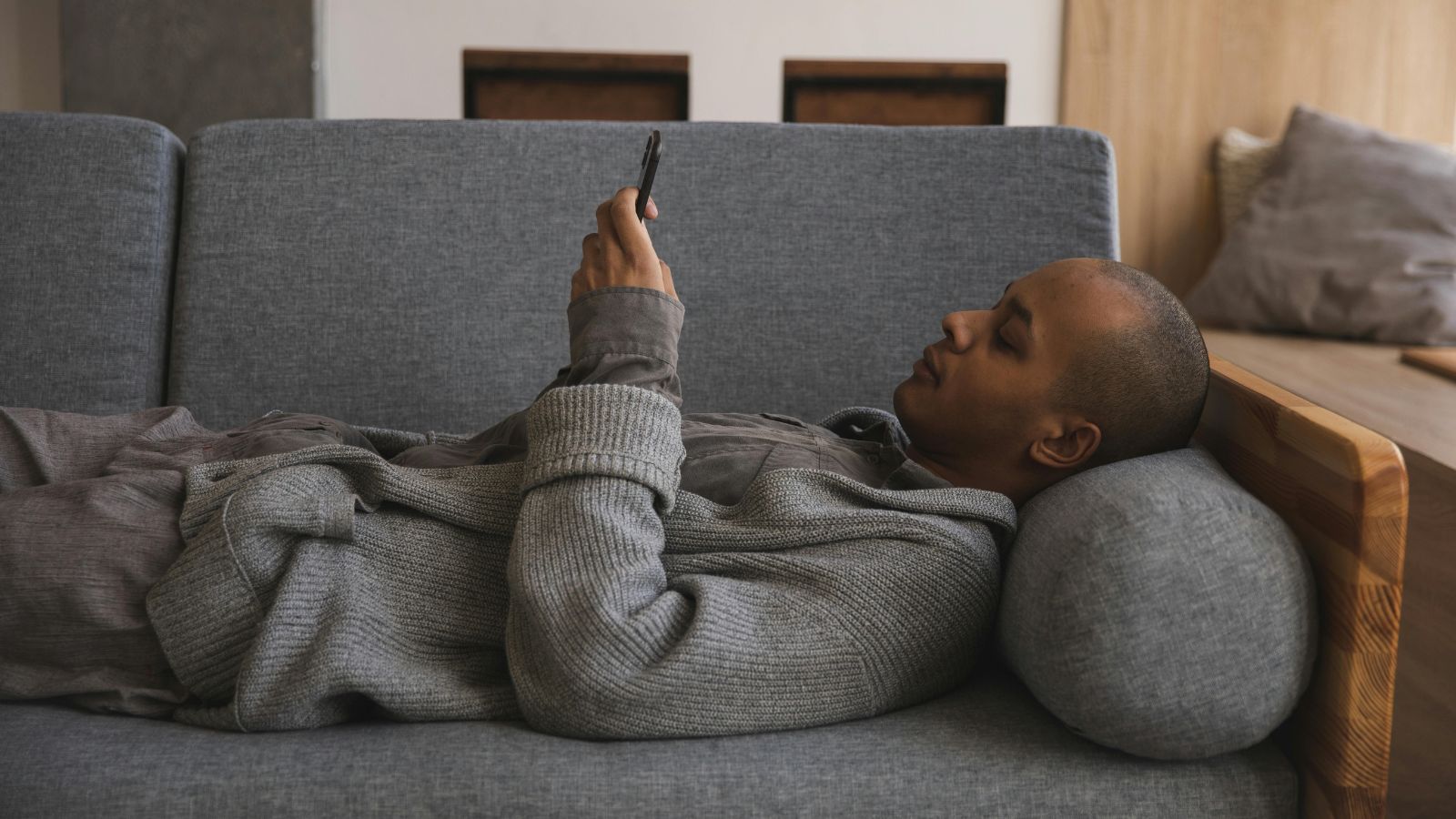 Man in grey hoodie laying on his couch