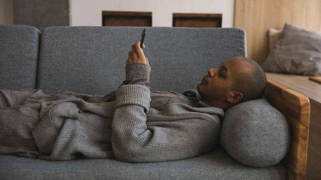 Man in grey hoodie laying on his couch