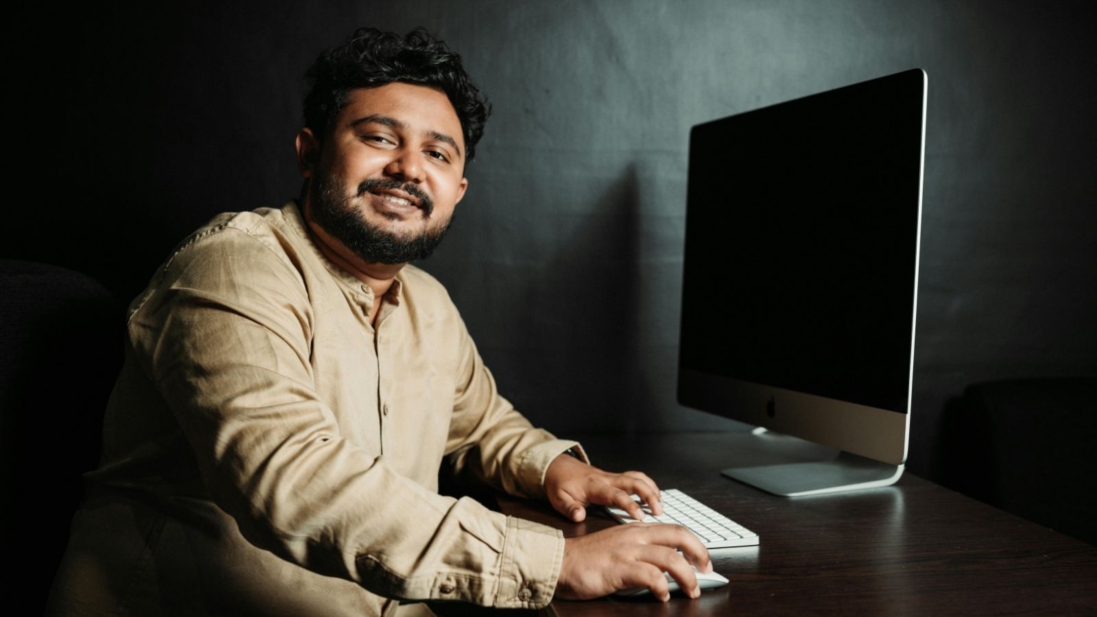 Man posing beside a computer