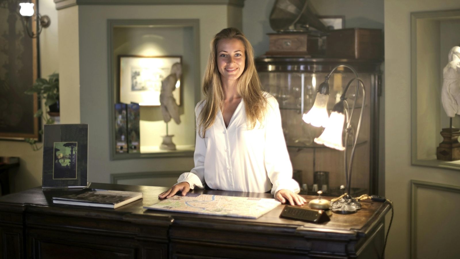 Hotel Clerk Calmly Refuses Guest’s Demand for a Free Night During Her Stay Hotel clerk smiles behind front desk