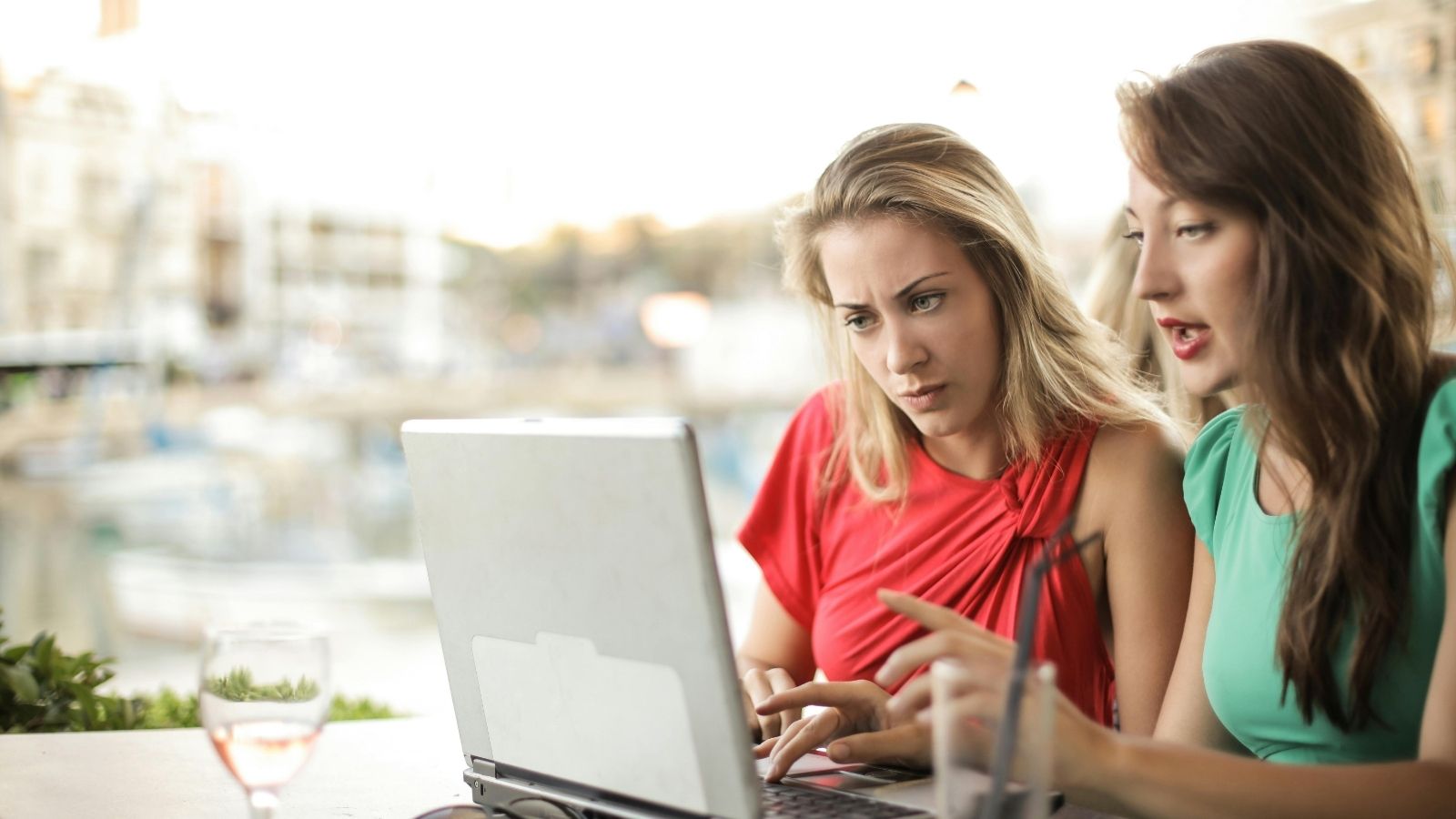 Two women seriously look at laptop outside