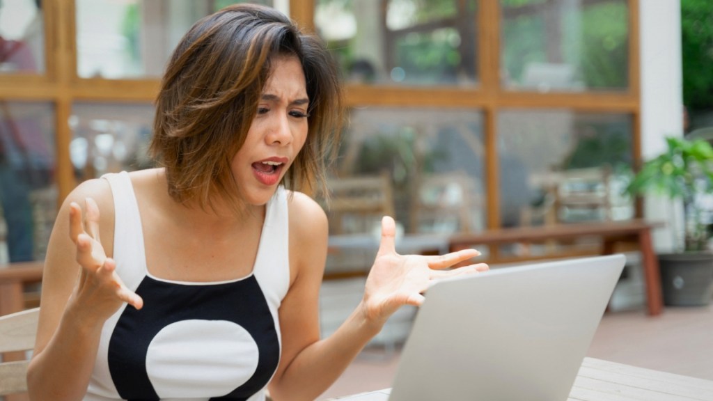 Upset woman using a laptop outside