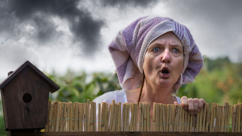 woman with a towel on her head yelling over the fence