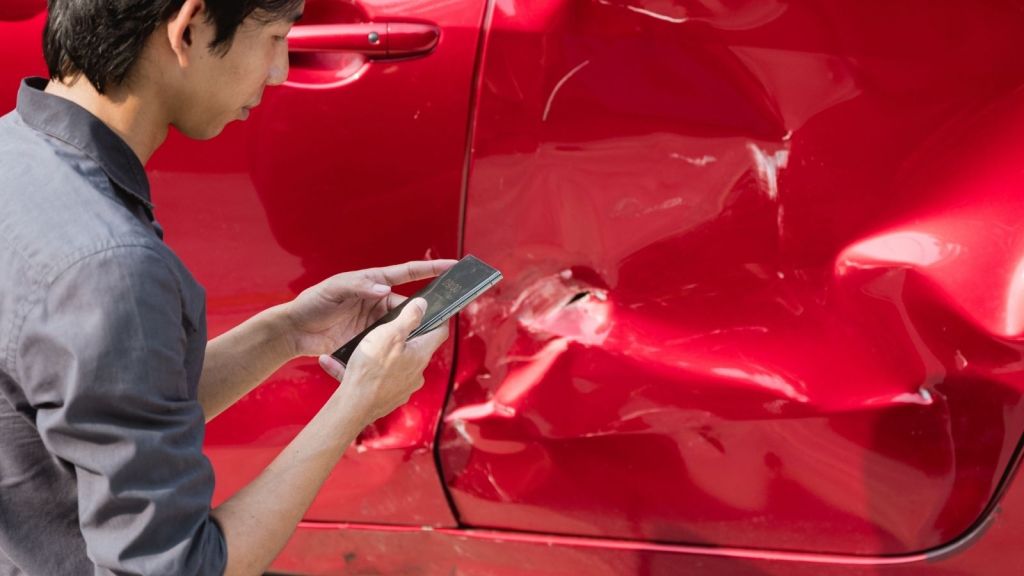man examining dented car