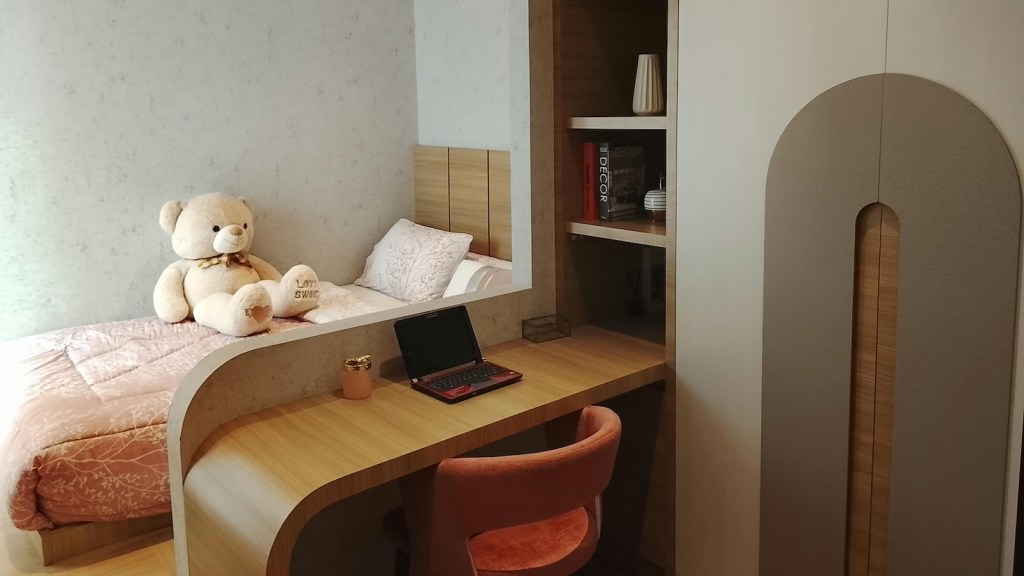 small bedroom with desk and teddy bear on bed