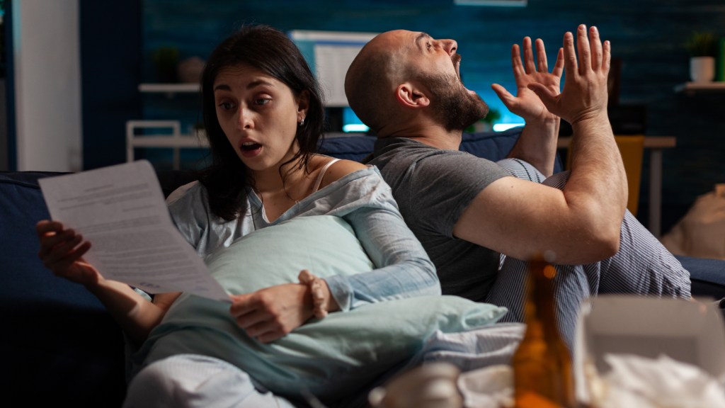 A couple freaking out about bills on their couch