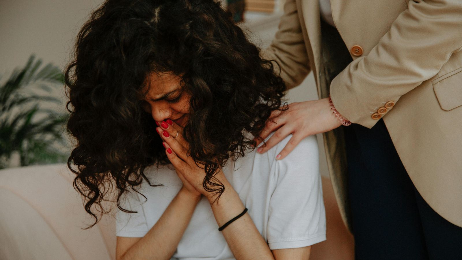 Woman crying while another comforts her