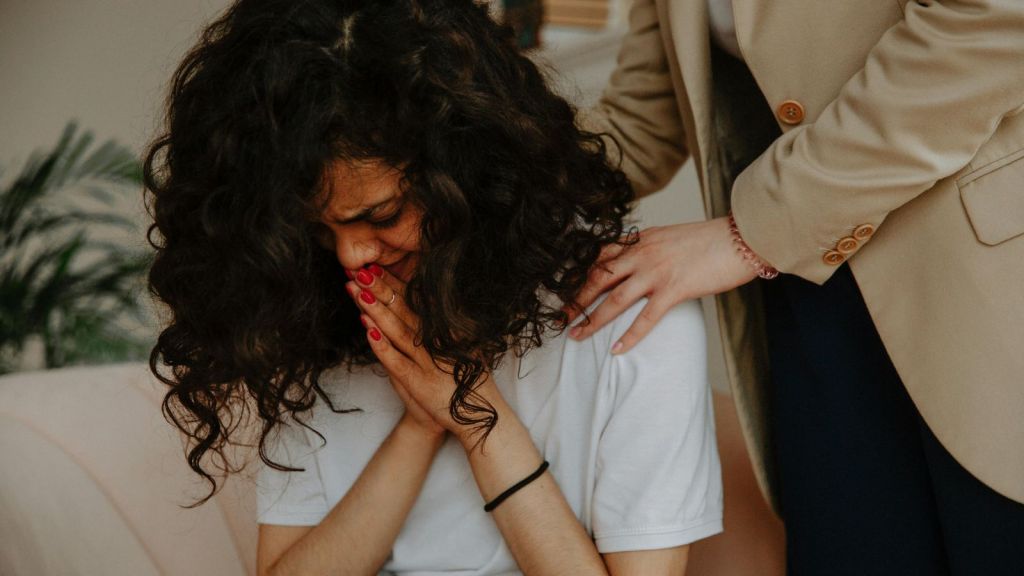 Woman crying while another comforts her