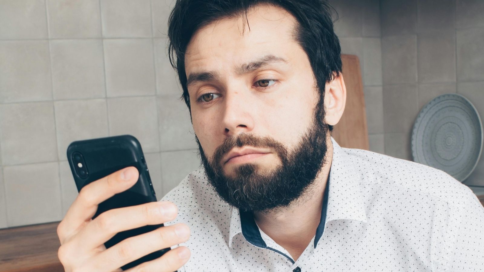 Man Considered Blocking Brother’s Manager After Being Texted Instead of His Brother for Work Shifts frustrated man looking at phone