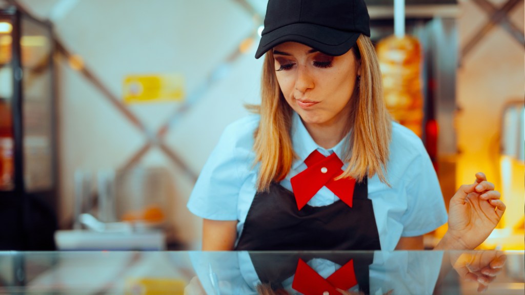 A frustrated fast food worker behind a counter
