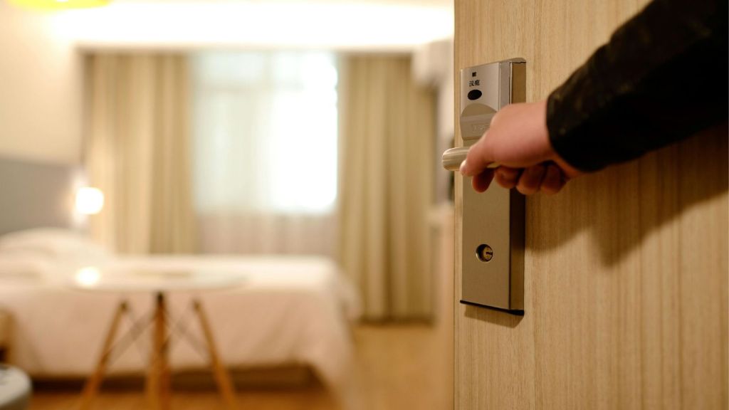 Man holding the door open to a hotel room