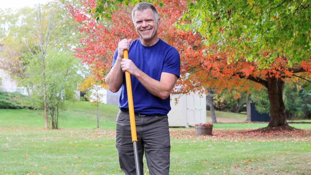 man raking leaves in yard