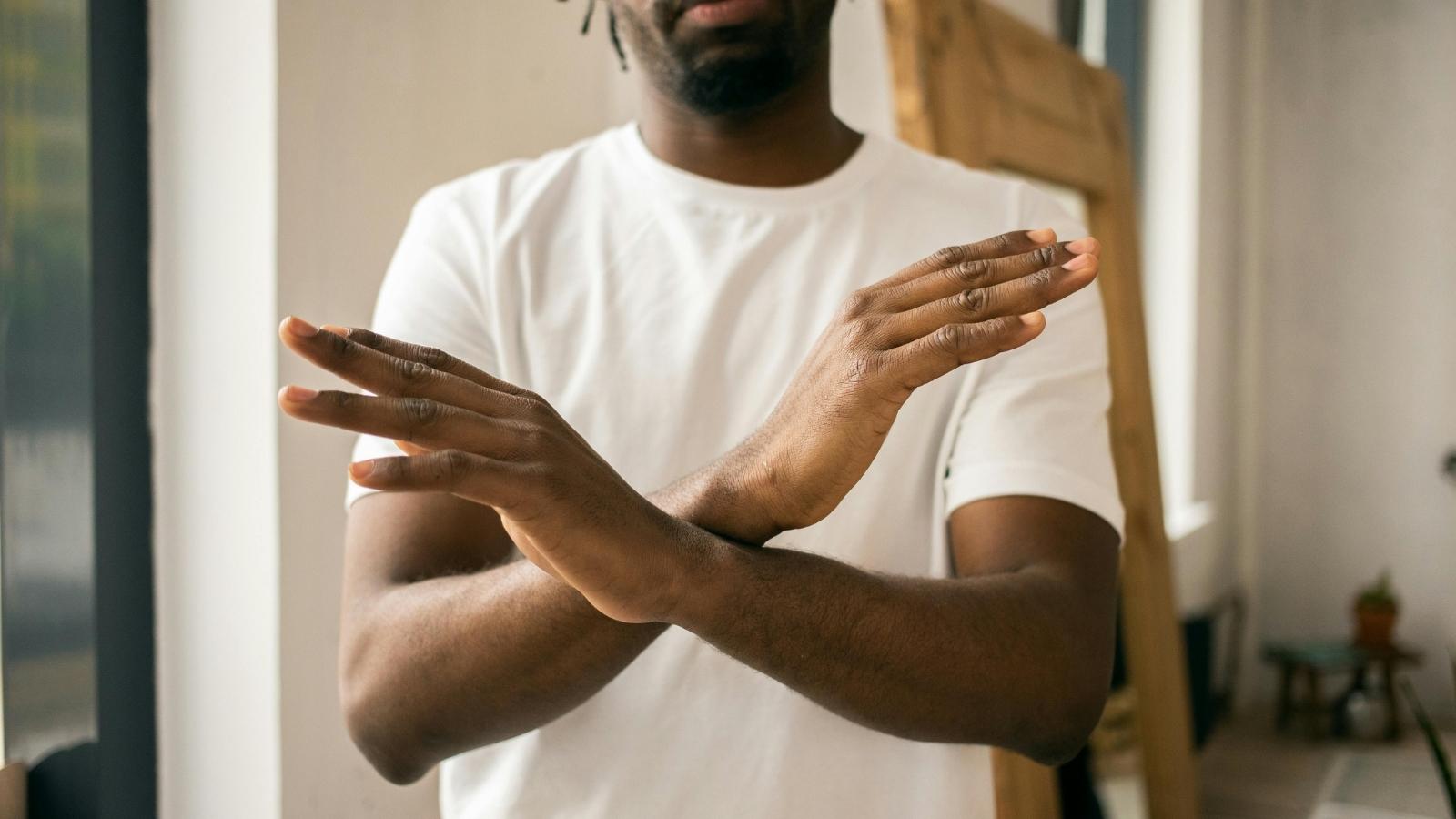 man gesturing an x with his hands