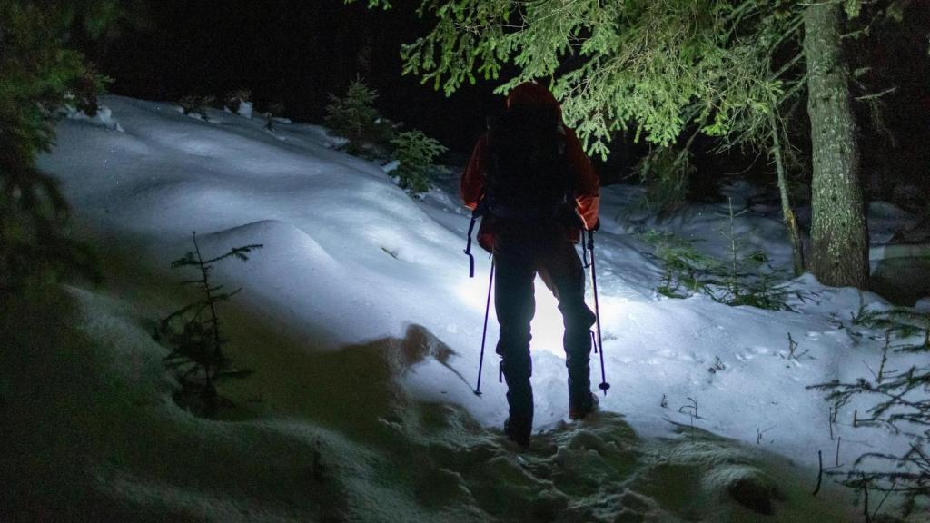 man hiking at night in the snow