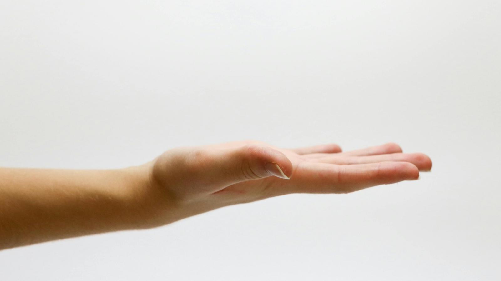 man holding out empty palm against white background