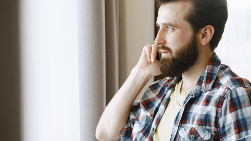Man looking out window talking on phone