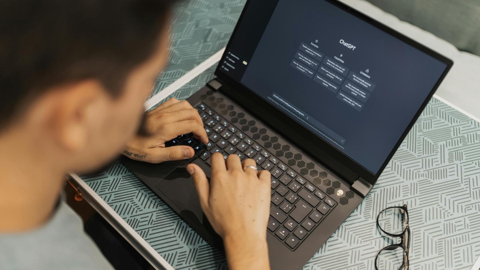 man typing into a laptop using AI