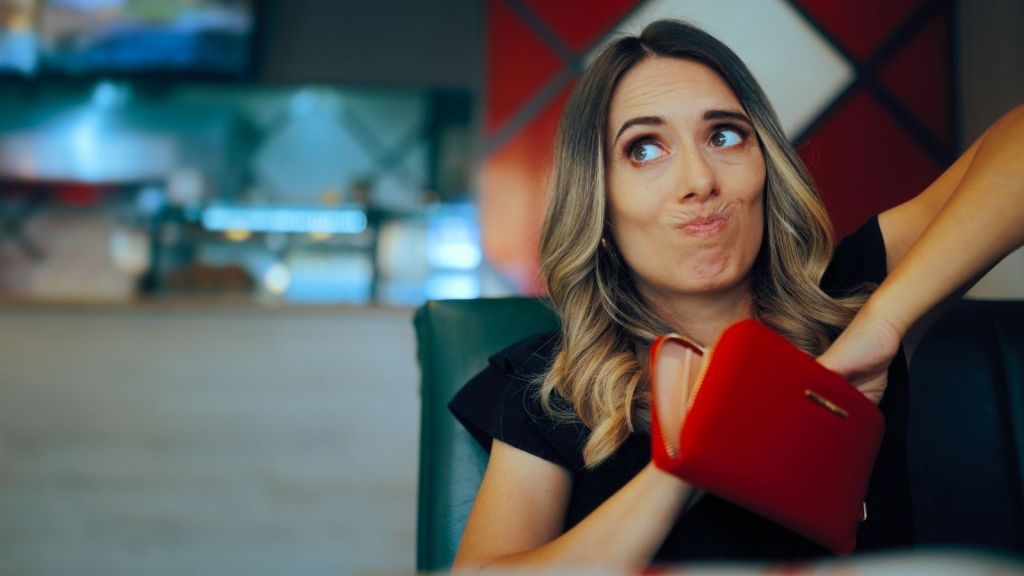 woman reaching into empty wallet