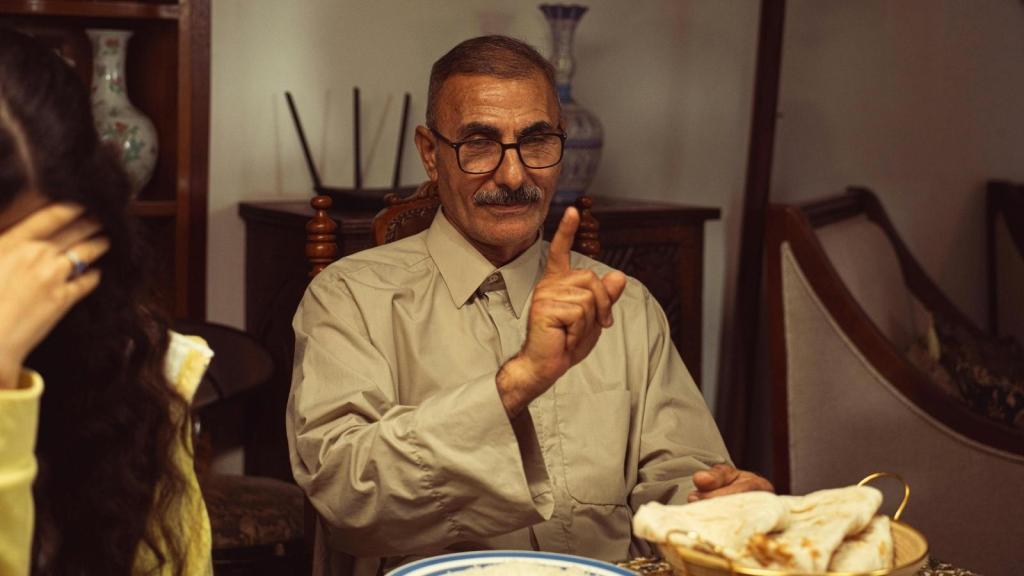 older man putting his finger up at the dinner table