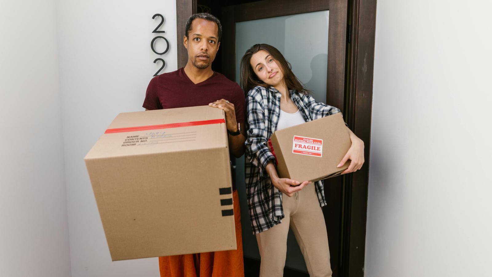 A Couple Finally Decided to Leave After Their Roommate Situation Reached a Breaking Point couple moving out and holding boxes