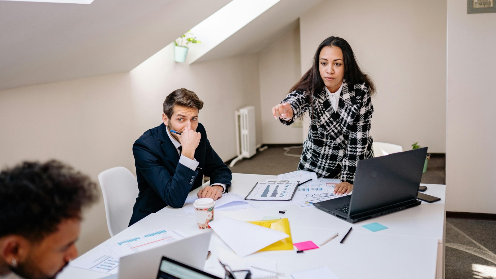 A woman pointing at a man in a meeting.